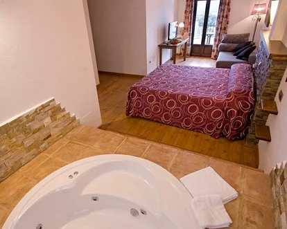 Bañera de hidromasaje junto a la cama en el hotel rural los Tadeos
