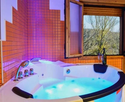 Jacuzzi con agua e iluminación de cromoterapia bajo la ventana con vistas