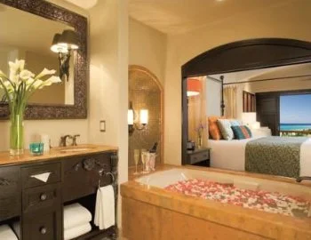La Suite Junior con vista parcial al mar y cama extragrande y foto de la bañera de hidromasaje que puedes disfrutar.
