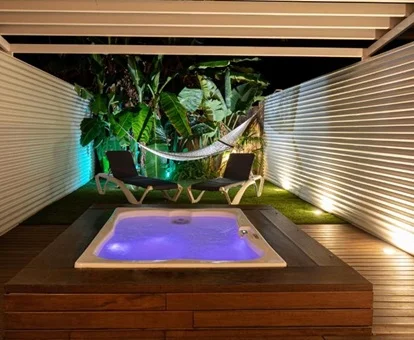 Foto de la terraza de la suite con el jardín al fondo y una jacuzzi sobre el suelo de madera con luz de color morado y bajo el techo de la terraza en el Hotel Tancat de Codorniu