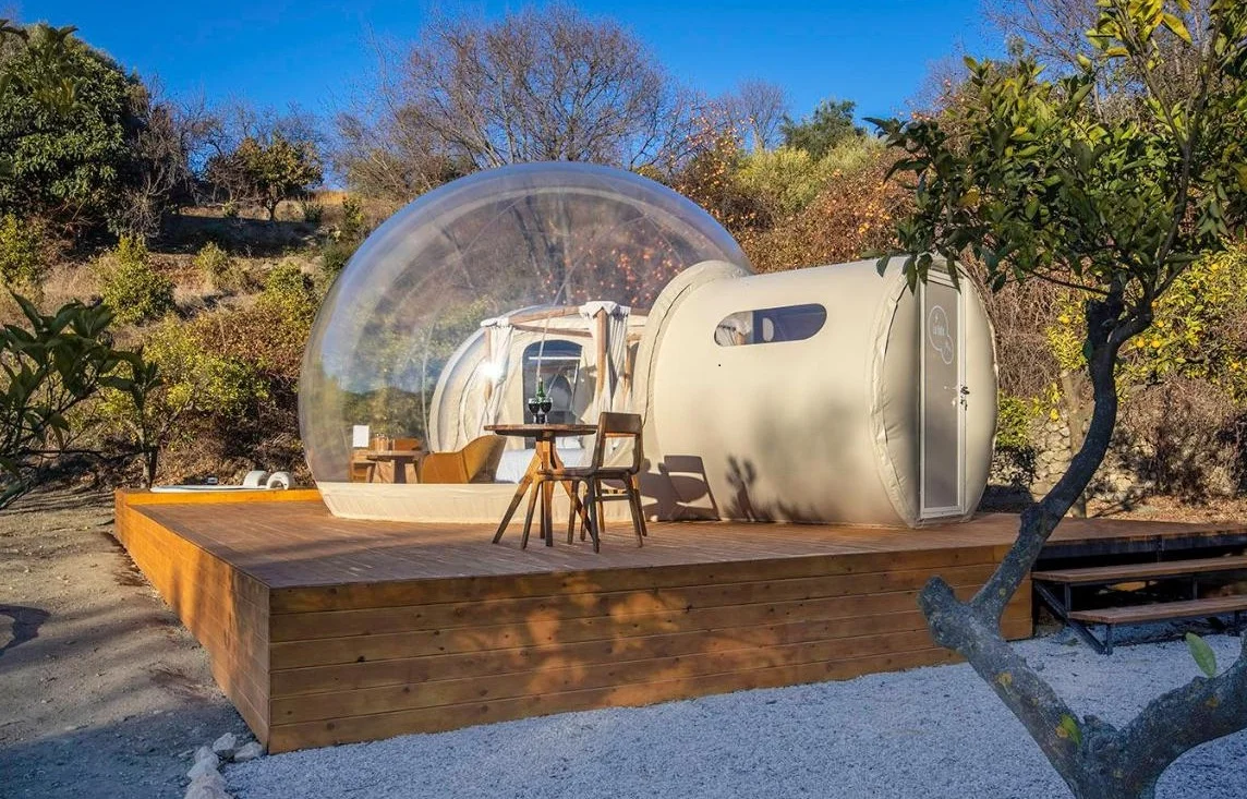 Foto del exterior de la suite burbuja en la La Bulle, con jacuzzi y suelo de madera en el exterior.