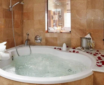 Foto de la bañera de hidromasaje en la suite del hotel Porto Cristo donde se ven unos pétalos de rosas en el borde del jacuzzi