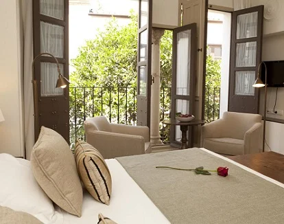 Foto del dormitorio de la Suite Superior con bañera de hidromasaje donde tienes unas vistas al patio del hotel.