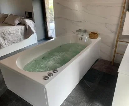 Amplio jacuzzi privado junto a la cama de este apartamento independiente.