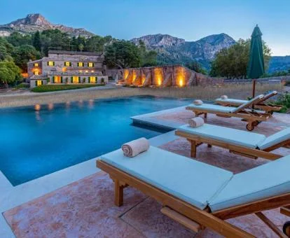 Gran piscina exterior con solarium y vistas a la naturaleza con el hotel al fondo.