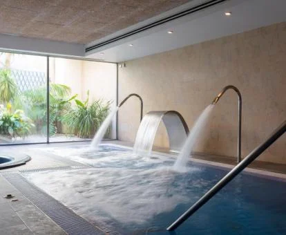 Piscina cubierta con hidroterapia y cristaleras con vistas al jardín.