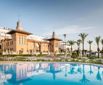 Precioso edificio palaciego de este hotel con piscina exterior y palmeras.