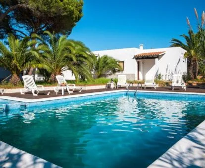 Complejo de apartamentos rurales con amplia piscina exterior con tumbonas y bellos jardines.