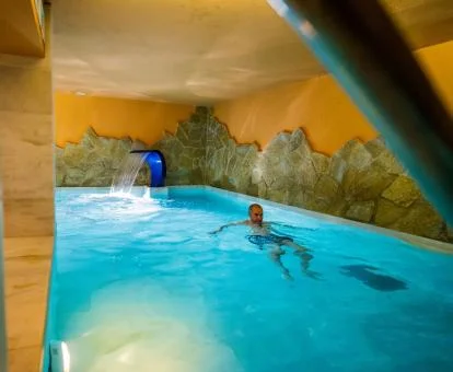 Hombre disfrutando de la piscina con elementos de hidroterapia del hotel.