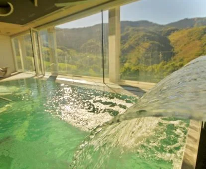 Preciosa piscina con elementos de hidroterapia y preciosas vistas a las montañas del spa del hotel.