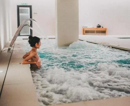 Mujer disfrutando de la piscina con elementos de hidroterapia del hotel.