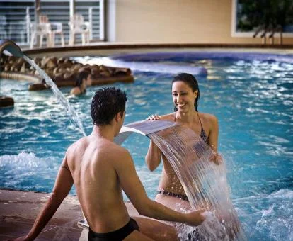 Pareja disfrutando de la piscina cubierta con instalaciones de hidroterapia del balneario del hotel.