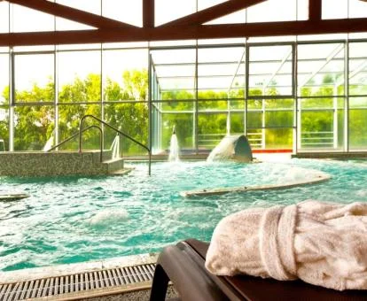 Piscina cuierta con elementos de hidroterapia y vistas al jardín del hotel.