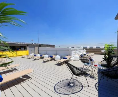 Terraza en la azotea del hotel con tumbona y mesas exteriores.