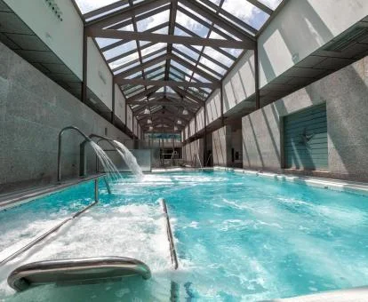 Preciosa piscina cubierta con elementos de hidroterapia del spa del hotel.