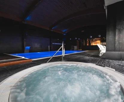 Jacuzzi circular en funcionamiento y la piscina cubierta del spa del hotel.