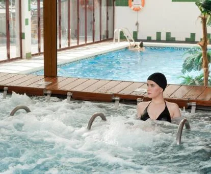Mujer disfrutando de la zona de aguas con hidroterapia del spa del hotel.