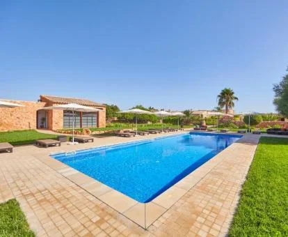 Amplia zona exterior con piscina y solarium rodeada de jardines de este hotel boutique.