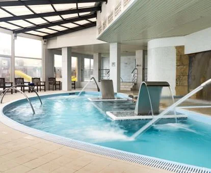 Piscina cubierta con hidroterapia y vistas al exterior del centro de bienestar del hotel.