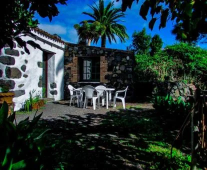Hermosa casa rural rodeada de jardines con comedor exterior.
