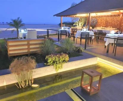 Zona exterior y comedor de este hotel solo para adultos junto al mar con iluminación nocturna.