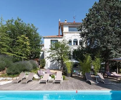 Foto de la fachada del hotel rodeada de árboles con piscina y solarium.