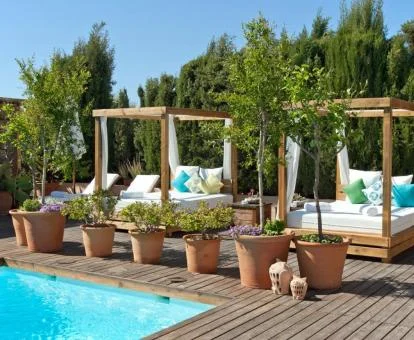 Solarium de la piscina al aire libre de este hotel con preciosas camas y rodeado de vegetación.