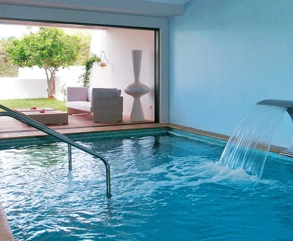 Piscina cubierta con chorros y vistas al jardín del spa del hotel.