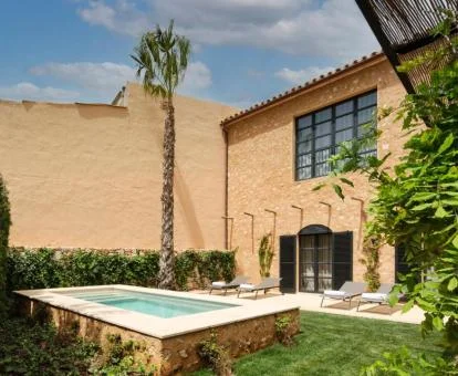 Piscina exterior privada de una de las suites en un hermoso jardín con tumbonas.