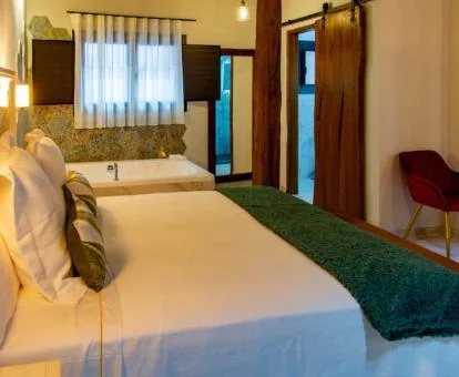 Precioso dormitorio con bañera de hidromasaje privada junto a la cama de uno de los apartamentos del establecimiento.