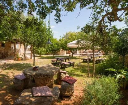 Zona exterior de este hotel rural con bellos jardines, árboles y mobiliario al aire libre.
