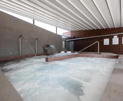 Piscina cubierta con elementos de hidroterapia del centro de bienestar del hotel.