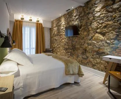 Una de las habitaciones con paredes de piedra a la vista y acogedora decoración de este hotel boutique.