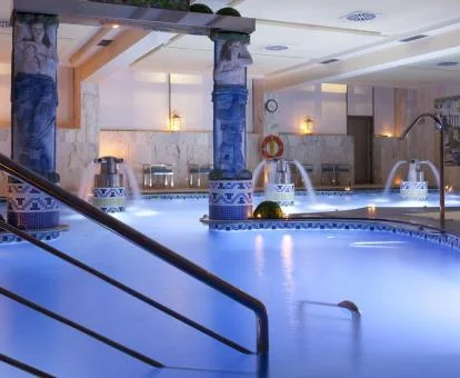 Gran piscina cubierta con elementos de hidroterapia del spa del hotel.