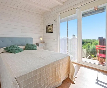 Foto del dormitorio con vistas al jardin y la zona de barbacoa desde la cabaña en el arbol