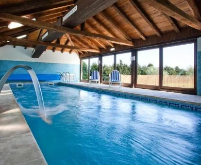 Piscina interior con chorros de hidroterapia y vistas al exterior del spa.