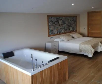 Dormitorio del apartamento deluxe de este establecimiento con un gran jacuzzi junto a la cama.