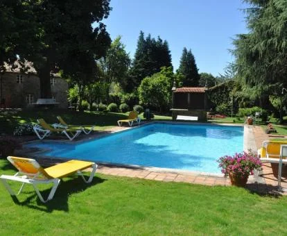Agradable zona exterior con piscina y solarium rodeada de jardines de este establecimiento.