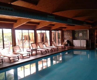 Piscina cubierta con zona de estar y vistas al exterior del spa del hotel.