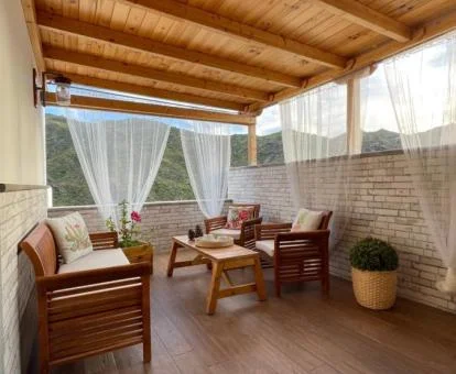 Terraza cubierta con mobiliario y vistas a las montañas de esta casa rural independiente.