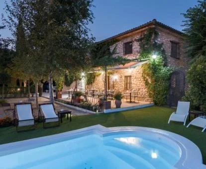 Alojamiento rural con piscina rodeada de jardines y terraza con mobiliario.