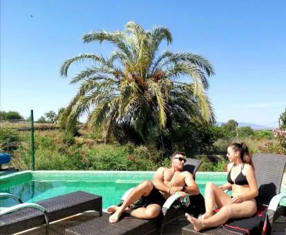 Pareja disfrutando del buen tiempo junto a la piscina de este hotel romántico.