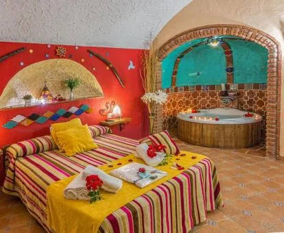 Dormitorio con jacuzzi privado cerca de la cama de una de las casas cueva del alojamiento.