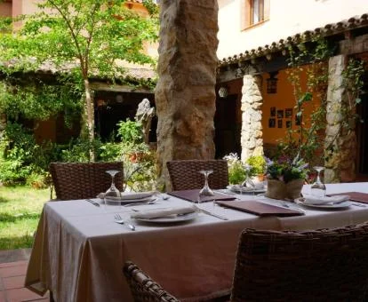 Bello patio interior con vegetación y comedor exterior de este hotel rural.