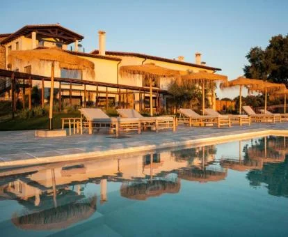 Precioso hotel con piscina exterior y tumbonas.