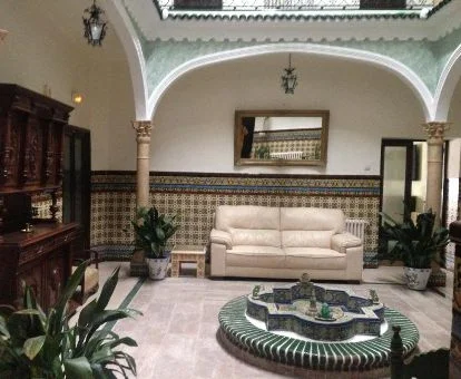 Patio interior de estilo andaluz con zona de estar y fuente de este hotel rural.