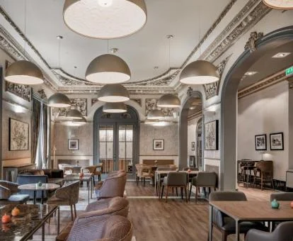 Elegante comedor con grandes lámparas y decoración en tonos grises.