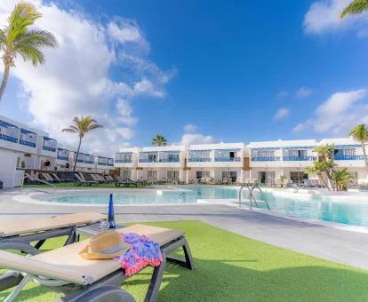 Hotel solo para adultos con piscina exterior, tumbonas y palmeras.