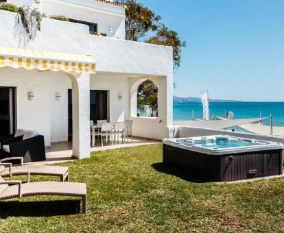 Jardín privado con vistas al mar y gran jacuzzi al aire libre del apartamento deluxe del establecimiento.