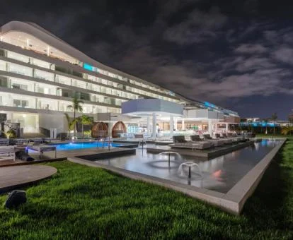 Edificio de este hotel con amplios jardines, piscinas y zonas de estar en el exterior.